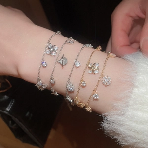 Detail of stacked gold and silver charm bracelets with sparkling zircon planet and star charms