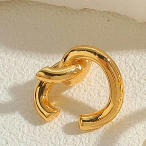 Macro shot of minimalist gold-plated knot ear cuff with a polished metallic texture finish