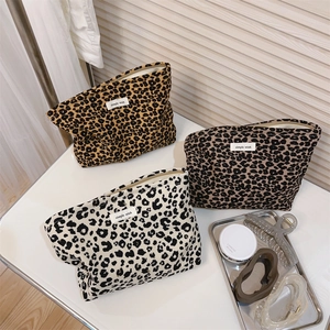 Flat lay of leopard print canvas makeup bags in brown, grey and black with zippers