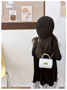 Rear view of a girl wearing a white quilted mini flap bag with golden chain and lock
