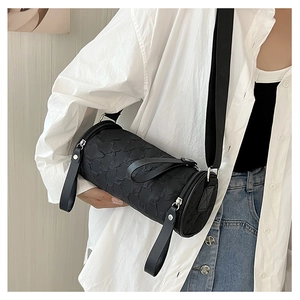 Close-up of black cylinder crossbody bag showing pleated texture and dual zipper detail