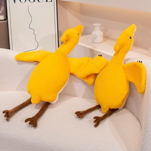 Close-up of two soft yellow pterosaur plush toys sitting on a white fabric sofa