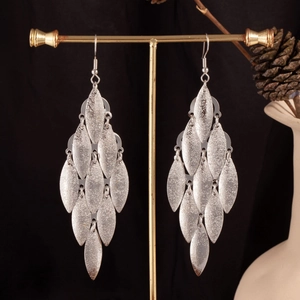 Detailed view of silver multi-layer leaf tassel earrings on a golden jewelry stand