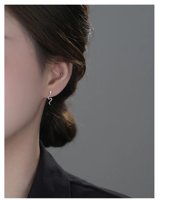 Close-up of silver snake-shaped earrings with micro flower stud on female ear model