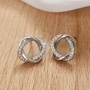 Macro view of intertwined silver knot stud earrings with white cubic zirconia inlay