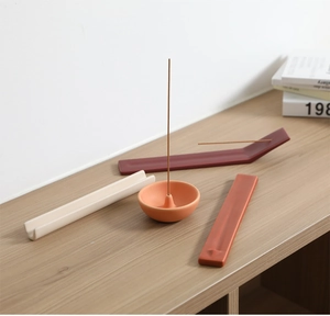 Detalle de porta inciensos cerámicos minimalistas con varias formas sobre madera