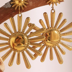Detailed view of sun-shaped 18K gold plated earrings hanging on a natural branch