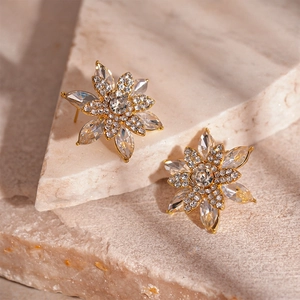 Detailed macro view of gold-tone layered flower stud earrings with sparkling cubic zirconia