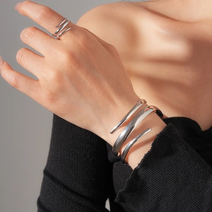 Nahaufnahme von dreilagigem silbernem Spiral-Armreif und passendem Ring-Set