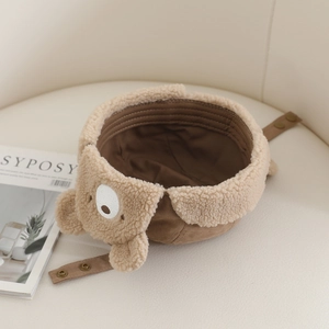 Winter kids plush trapper hat with cute bear ears and embroidery on a beige sofa