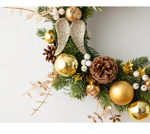 Detail of Christmas wreath with golden balls, pine cones, and gold angel wings décor