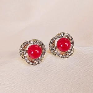 Elegant gold spiral stud earrings with sparkling crystals and a central red pearl