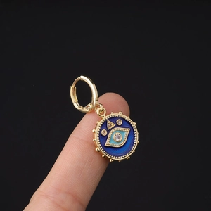 Golden huggie hoop earring featuring a blue enamel evil eye charm with a white zircon