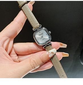 Close-up of minimalist square quartz watch with silver case and grey leather strap