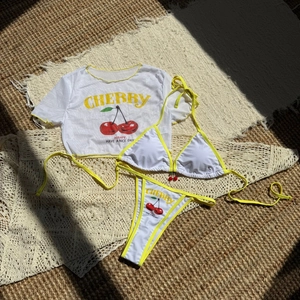 Detailed view of 3-piece bikini set with white mesh cover-up and cherry prints