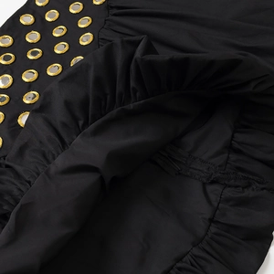 Vue détaillée du tissu noir avec accents de miroir doré et design à volants plissés