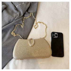 Detail of gold evening bag with glitter texture, rhinestone buckle and chain strap