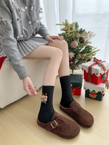 Close-up of black ribbed Christmas socks with 3D reindeer doll and stylish buckled clogs