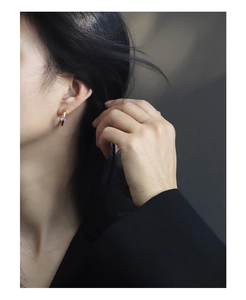 Close-up of elegant gold C-shaped hoop earring with square zircon on a female model