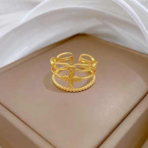Detail view of a gold-plated adjustable four-leaf clover ring on a brown jewelry box