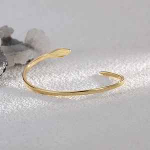 Minimalistisches goldfarbenes Schlangen-Armband mit verstellbarem Design auf weißem Steingrund