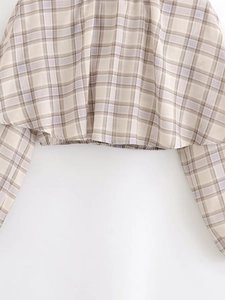 Detail of checkered blouse with elastic hem and beige-purple plaid fabric texture