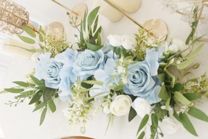 Detailed view of artificial blue rose floral arrangement with green leaves and white buds