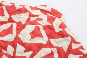 Gros plan du tissu matelassé avec motif géométrique d'étoiles rouge et beige