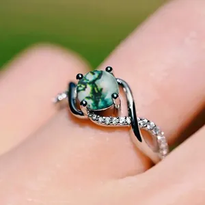 Elegante zilveren ring met ronde mosagaat en pavé-accenten in een gedraaid bandontwerp