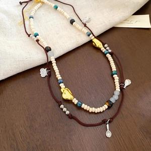 Detail of layered boho necklace with silver butterfly pendant and natural wooden beads