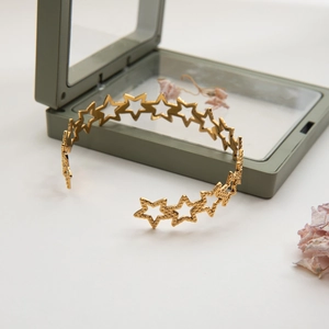 Detailed view of gold plated stainless steel open bangle with hammered star cutouts