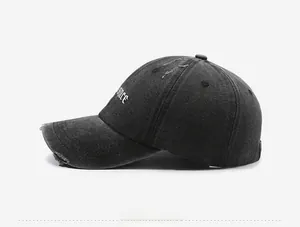 Detailed side view of washed dark grey denim baseball cap with gothic embroidery and distress