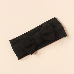 Detail shot of a black ribbed knit bow headband for infants on a neutral background