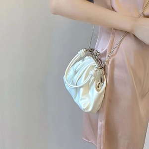 Close-up of white pleated cloud bag with silver metal clasp and knotted top handle