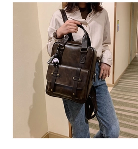 Detail of dark brown vintage leather backpack featuring cute panda plush charm accessory