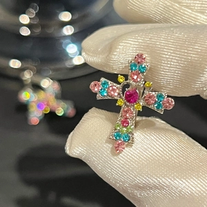 Detailed macro view of silver cross earring with vibrant multi-color zircon inlay