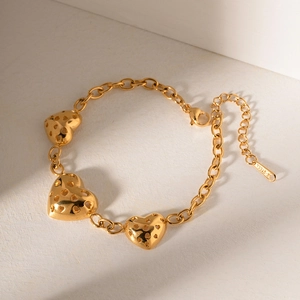 Detail view of gold stainless steel bracelet with hollow heart charms and S.STEEL stamp