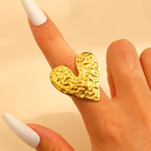 Detailed view of large gold heart-shaped ring with hammered metal texture on hand