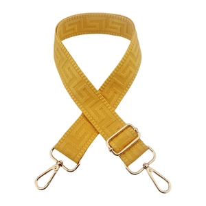 Macro detail of mustard yellow geometric jacquard strap with gold metal swivel snap hooks
