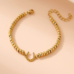 Detail of 18K gold-plated beaded bracelet with horseshoe pendant and lobster clasp