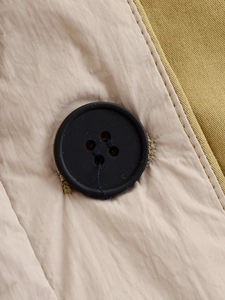 Detail view of black buttons and khaki fabric texture with high-quality stitching on jacket