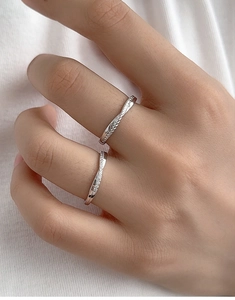 Close-up of S925 silver rings with twisted texture and micro-set zircon on white fabric