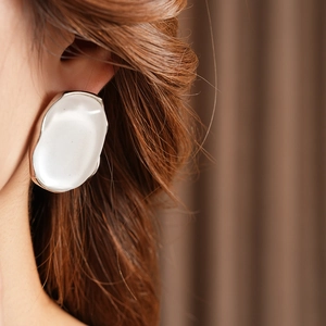 Close-up of minimalist oval resin earring with wavy silver metallic border on model