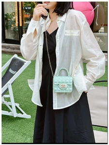 Detail of mint green quilted jelly bag with metal chain and twist handle in lifestyle setting
