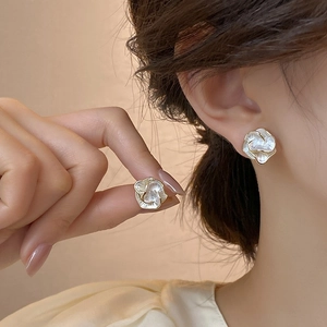 Detail of white flower stud earrings with gold edges and pearl texture on ear