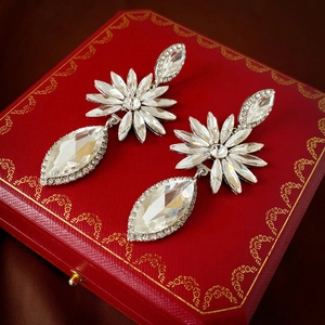 Dettaglio orecchini a goccia con fiori e cristalli su una scatola porta gioie rossa