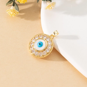 Macro view of gold Evil Eye pendant with zircon inlay on a white ceramic dish