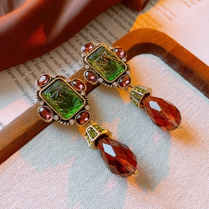 Close-up of vintage bronze earrings with green gemstone and amber crystal drops