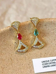 Macro shot of asymmetrical 14K gold plated fan earrings with red and green teardrop gems