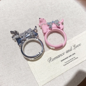 Macro detail of dog rings with zircon bows and pearls on a textured background